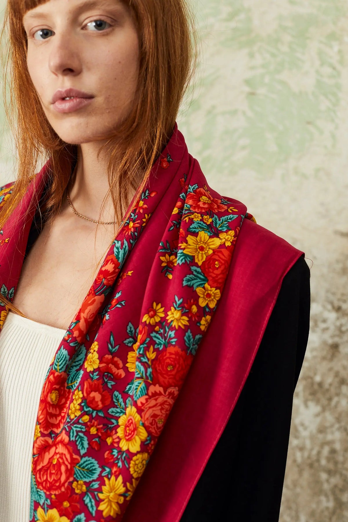 Pañuelo portugués rosa con estampado floral tradicional de flores rojas, amarillas y hojas verdes sobre tejido suave.