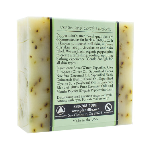 Rectangular bar of peppermint soap with botanical flecks, wrapped in a label detailing ingredients and vegan benefits.