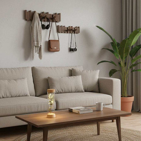 Perchero de pared de madera natural con ganchos plegables de estilo escandinavo, instalado sobre un sofá beige.