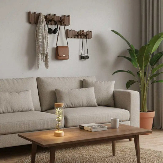 Perchero de pared de madera natural con ganchos plegables de estilo escandinavo, instalado sobre un sofá beige.