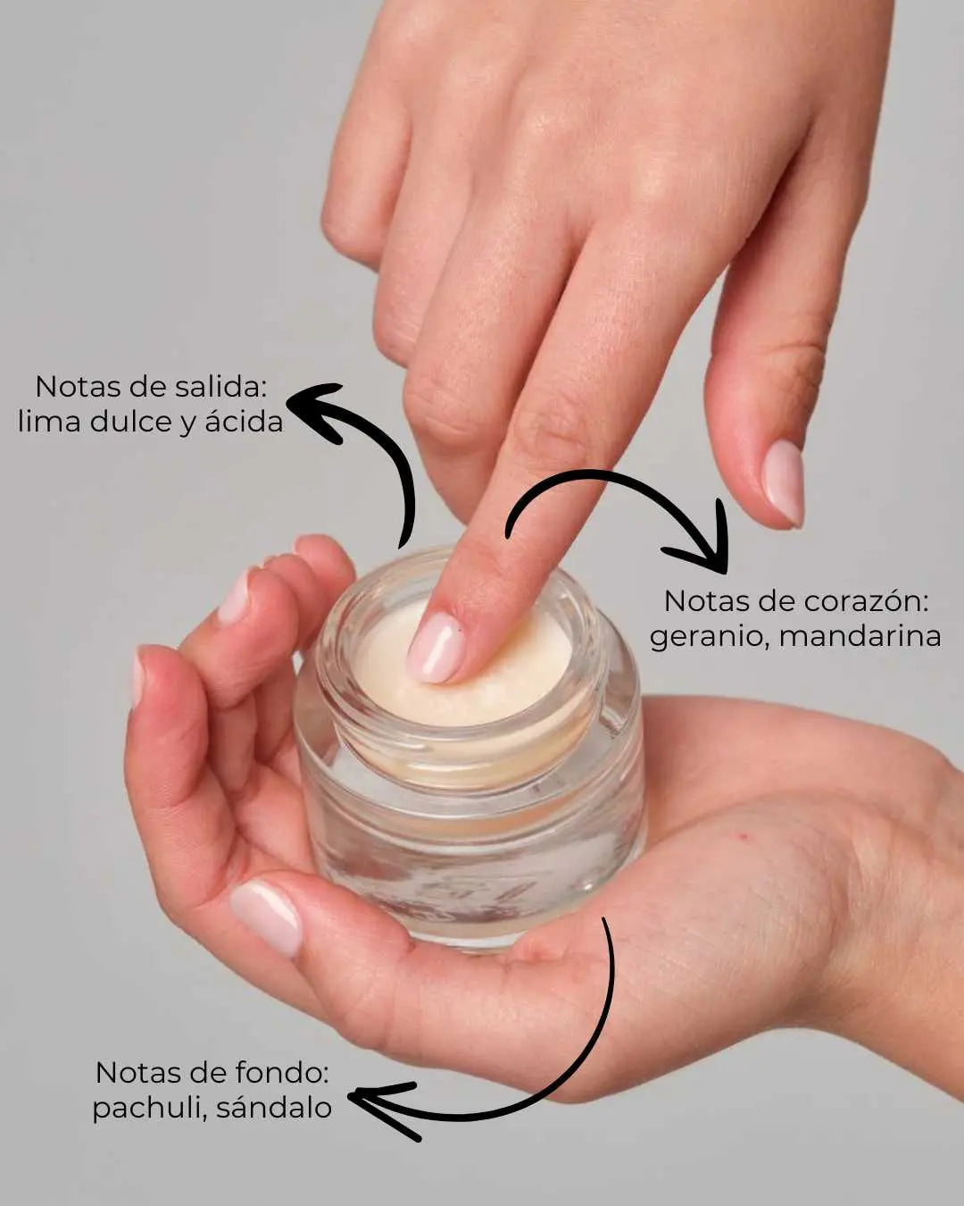 Manos sosteniendo un tarro de cristal con perfume sólido Banbu, mostrando su textura cremosa y sus notas aromáticas.
