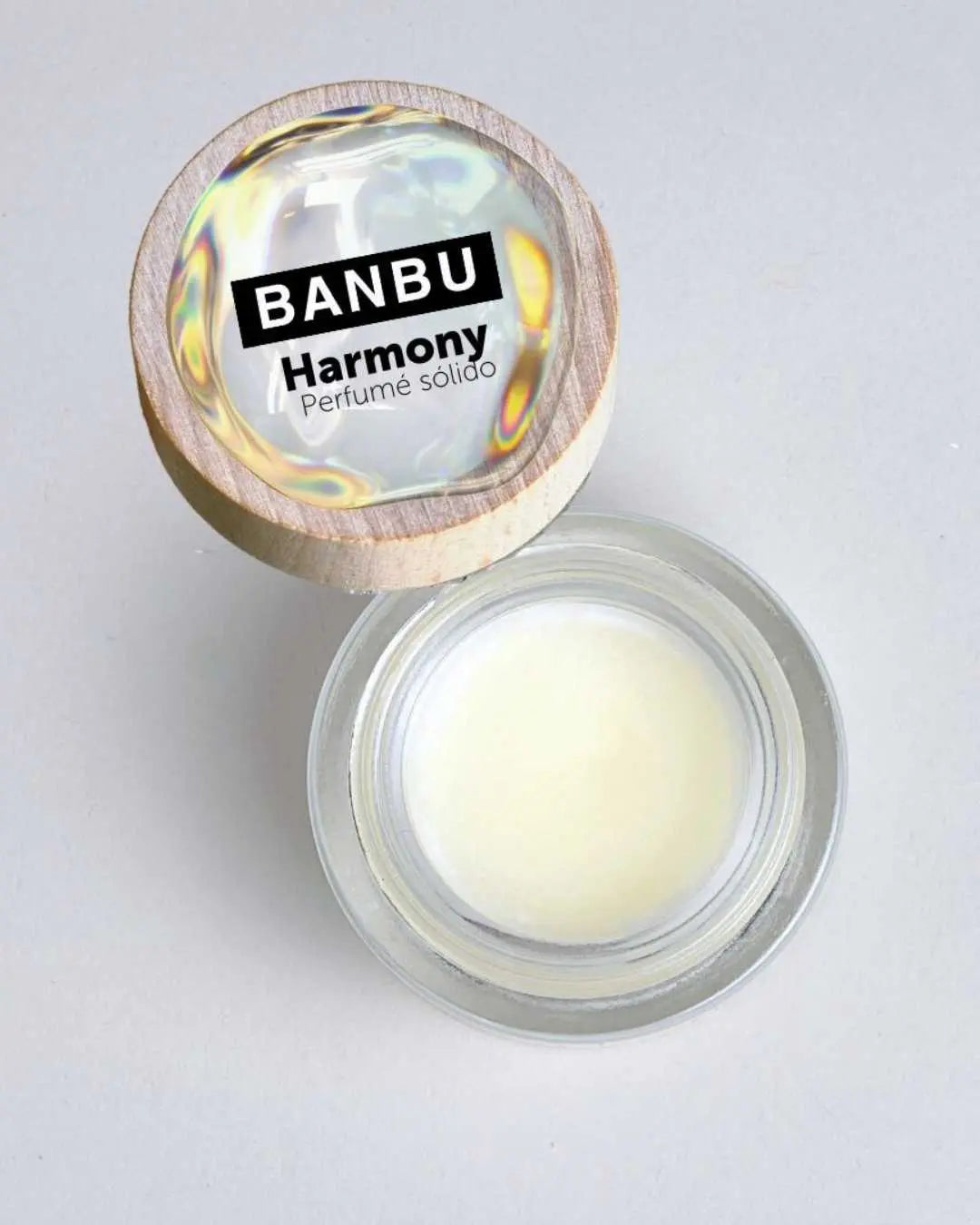 Perfume sólido Banbu Harmony en tarro de vidrio con tapa de madera y etiqueta iridiscente sobre fondo gris claro.