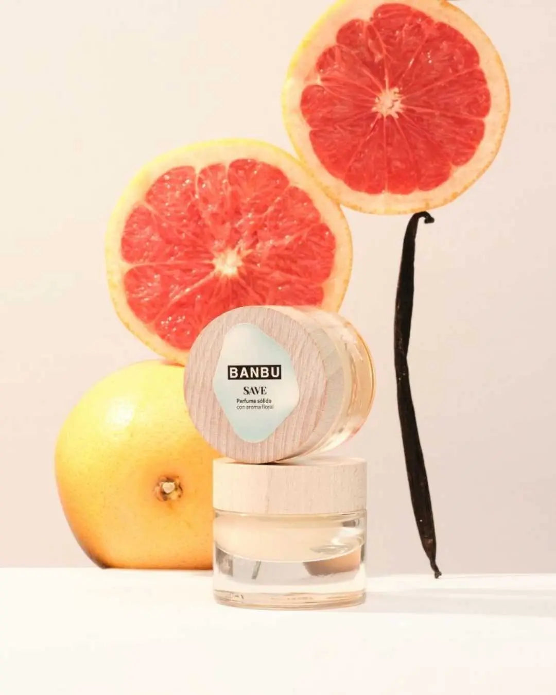 Perfume sólido Banbu SAVE con tapa de madera sobre pomelos y vainilla, transmitiendo frescura natural y ecológica.