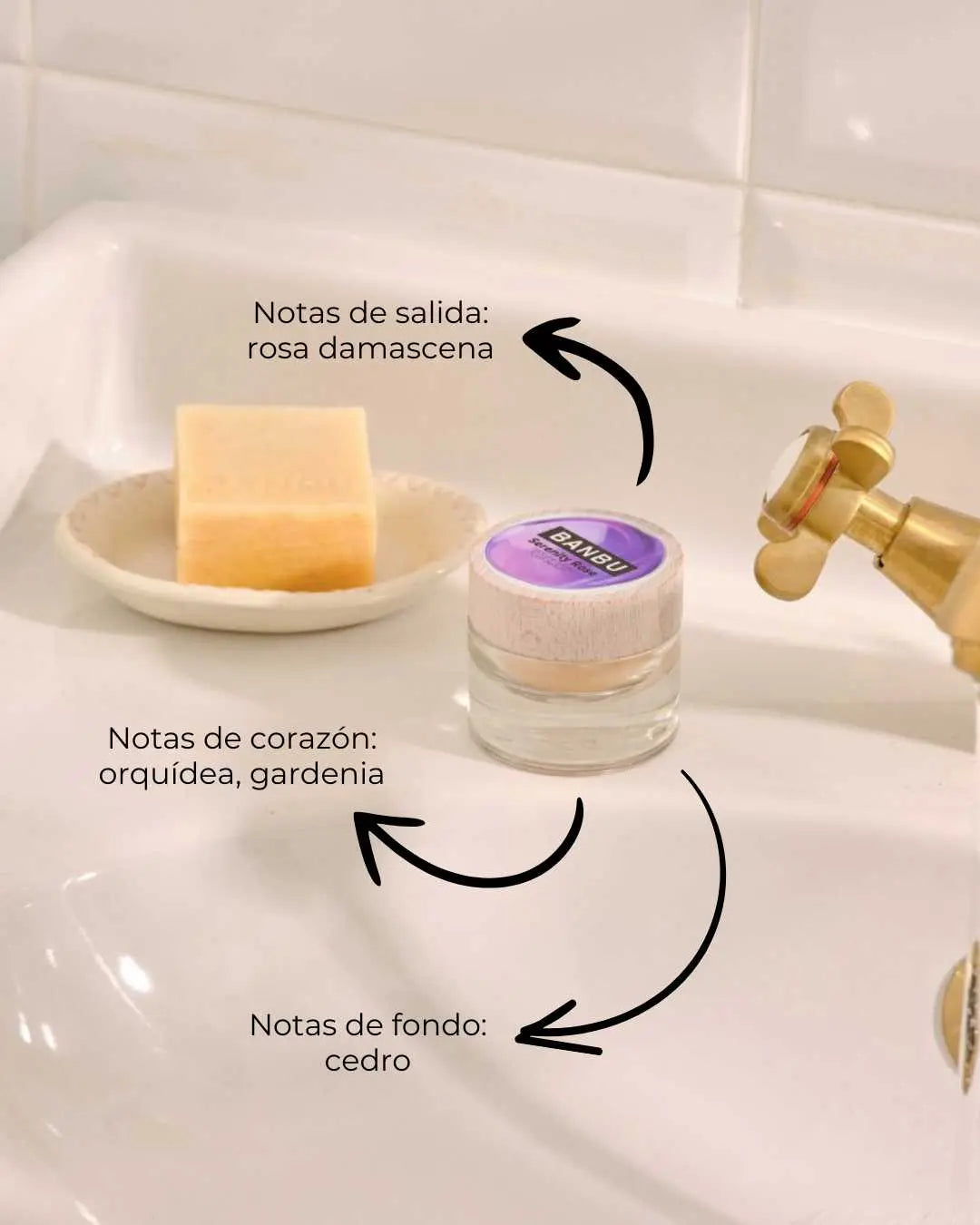Perfume sólido Banbu en tarro de cristal con tapa de madera junto a una pastilla de jabón sobre un lavabo blanco.