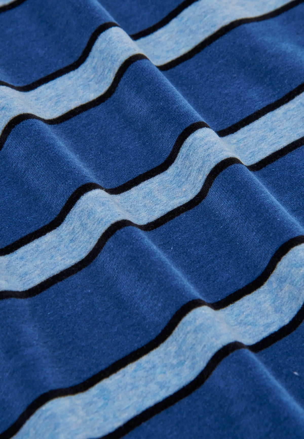 Detalle de tejido de terciopelo suave para pijama de hombre con rayas horizontales en tonos azul oscuro y celeste.