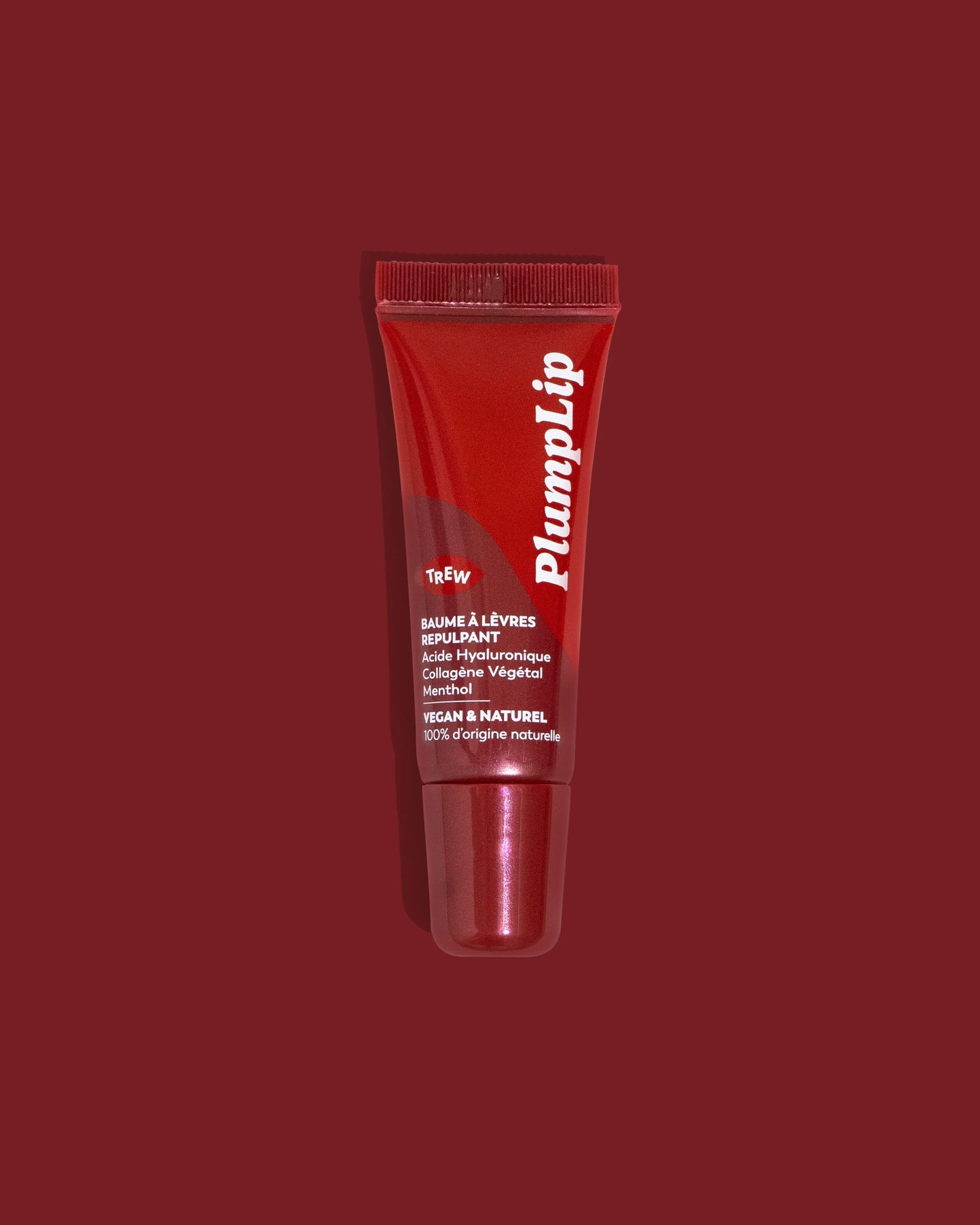 Tube rouge brillant PlumpLip de Trew Cosmetic sur fond assorti. Texte blanc lisible, embout applicateur intégré.