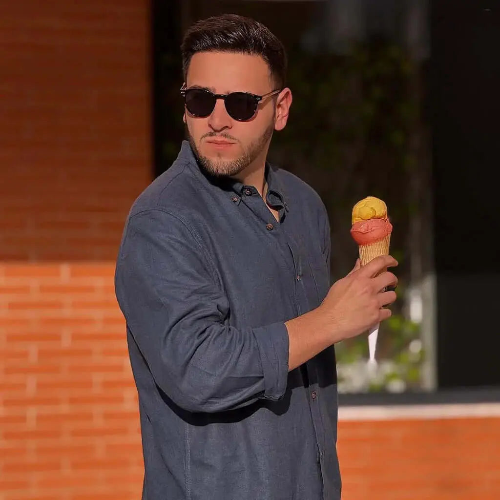 Hombre con camisa azul y helado, luciendo gafas de sol de carey con lentes polarizadas marrones de estilo clásico.