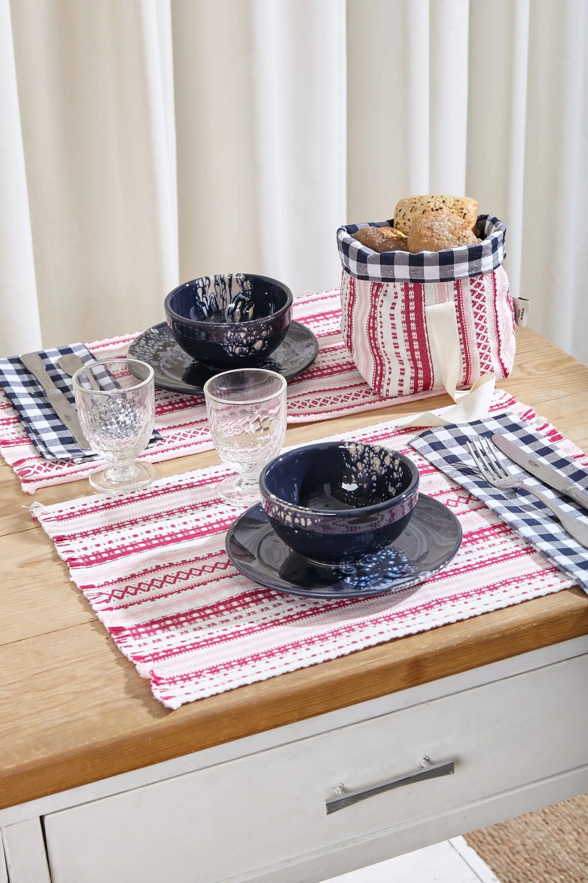 Pack de dos manteles individuales de estilo alpujarra en tonos rosas y blancos con textura tejida sobre mesa de madera.