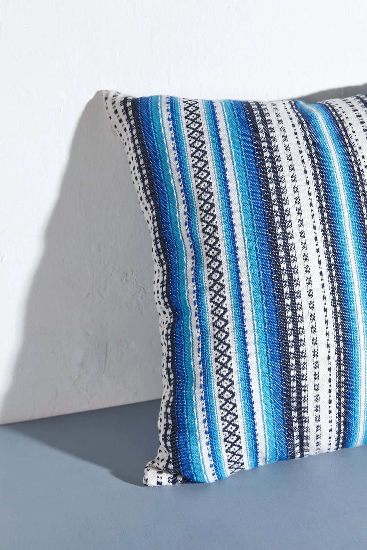 Funda de cojín de 50x50cm con diseño alpujarreño a rayas en tonos azules y blancos, tejido artesanal de textura rústica.