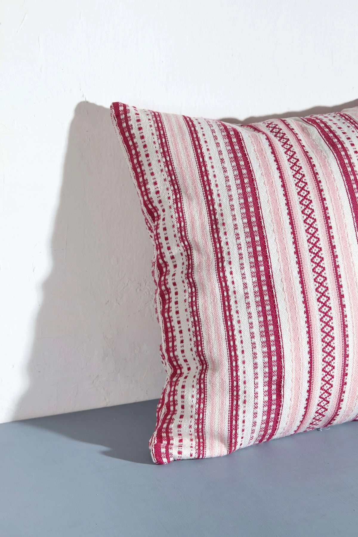 Funda de cojín cuadrada (50x50cm) con diseño de rayas verticales en tonos rosas y texturas artesanales tipo alpujarra.
