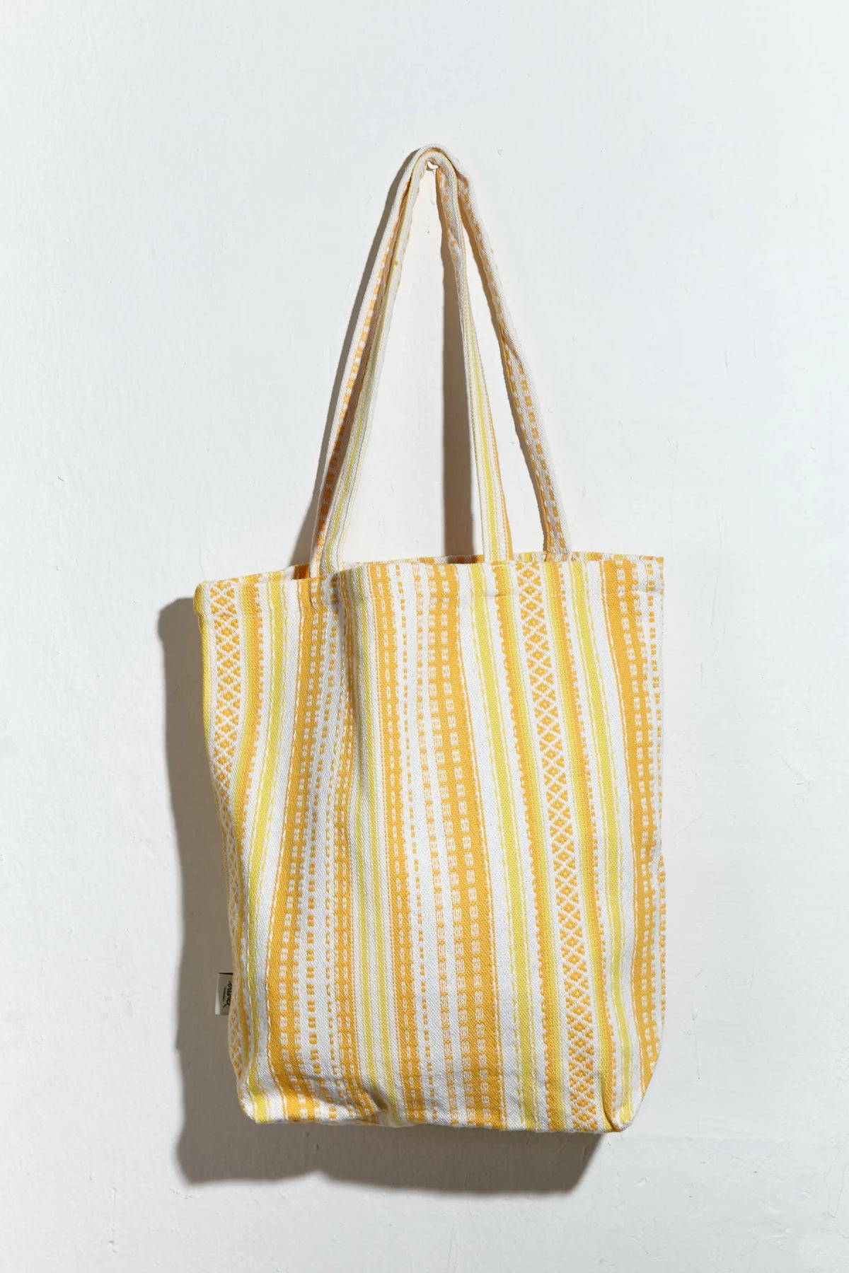 Tote bag de tela con estampado de rayas verticales en tonos amarillos y blancos y diseño artesanal tipo Alpujarra.