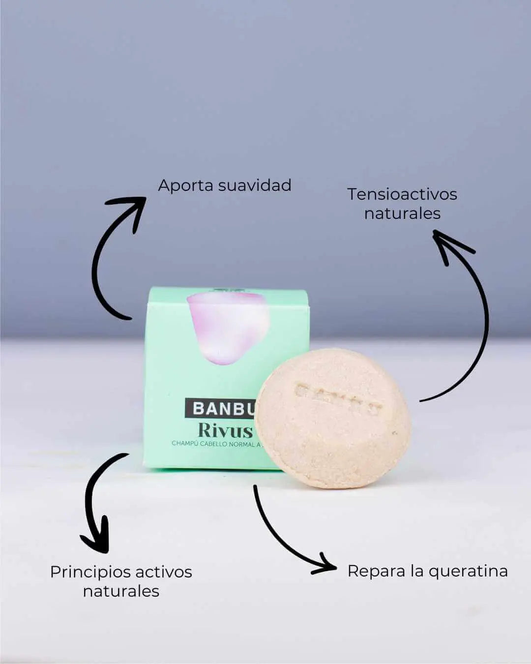 Champú sólido Banbu Rivus frente a su caja verde, con flechas que señalan sus beneficios naturales y reparadores.