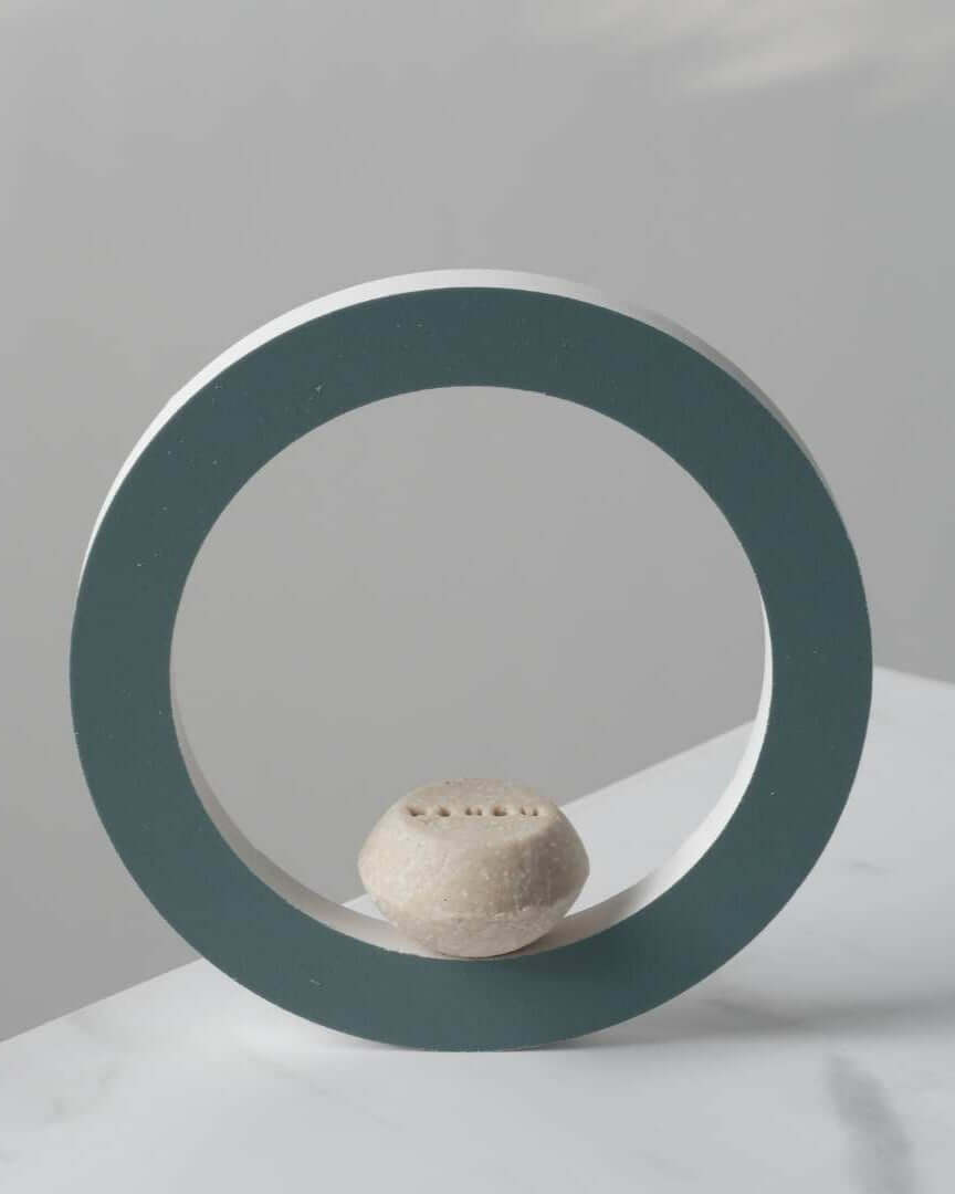 Champú sólido hidratante Banbu sobre un círculo decorativo azul sobre fondo blanco. Estética minimalista y natural.
