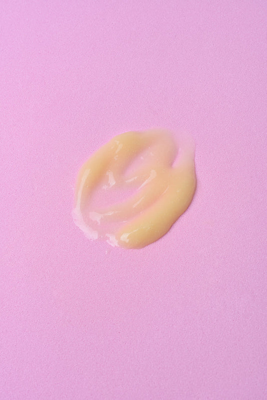 Crema hidratante amarilla en textura suave sobre fondo rosa. Ideal para piel seca y sensible.