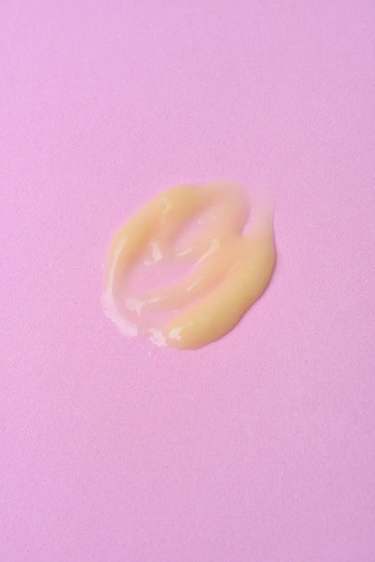 Crema hidratante amarilla en textura suave sobre fondo rosa. Ideal para piel seca y sensible.
