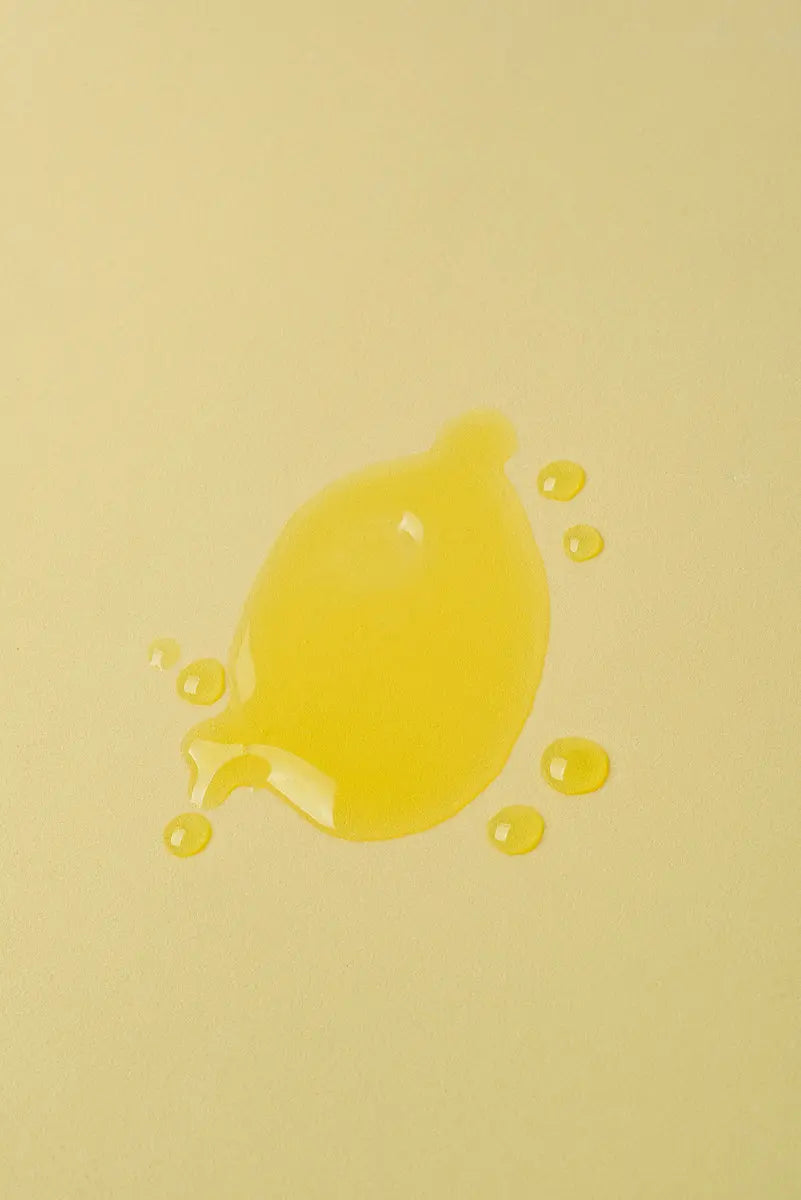 Gota de aceite amarillo brillante sobre fondo amarillo suave, ideal para productos de belleza o cocina.