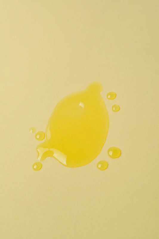 Gota de aceite amarillo brillante sobre fondo amarillo suave, ideal para productos de belleza o cocina.