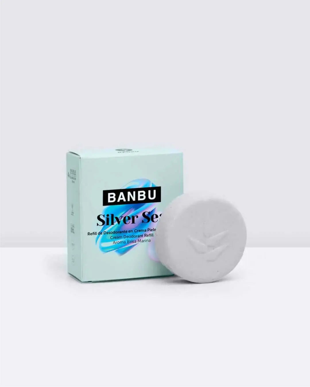 Caja de cartón azul claro Banbu junto a un bloque sólido redondo de desodorante en crema color blanco.