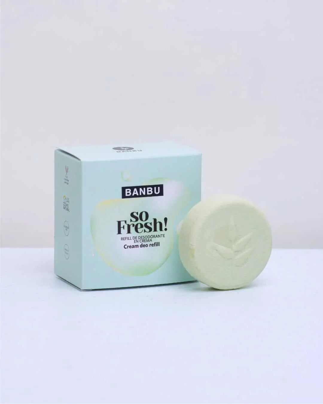 Caja de cartón azul claro y pastilla de desodorante en crema color verde suave con logo de hoja de la marca Banbu.