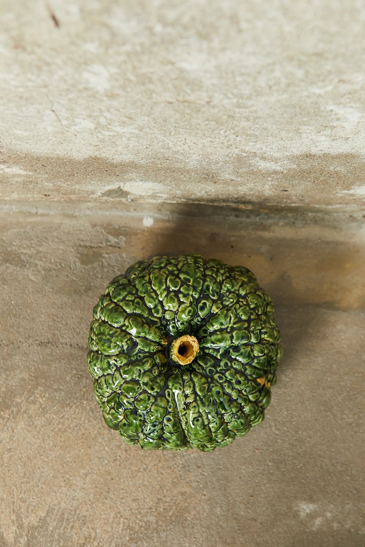 Calabaza verde de cerámica brillante con textura arrugada, ideal para decoración rústica y artesanal.