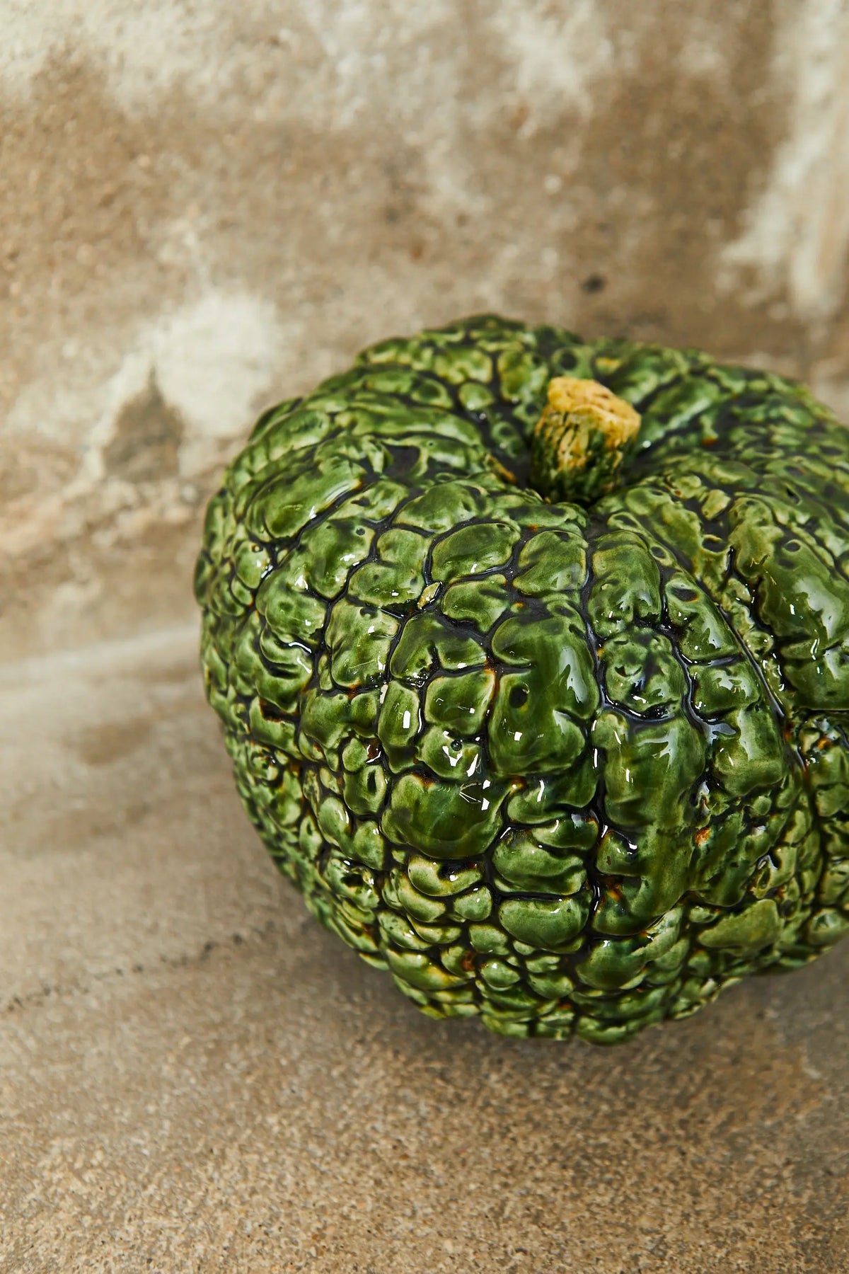 Calabaza decorativa de cerámica verde brillante con textura arrugada, ideal para adornos rústicos y naturales.
