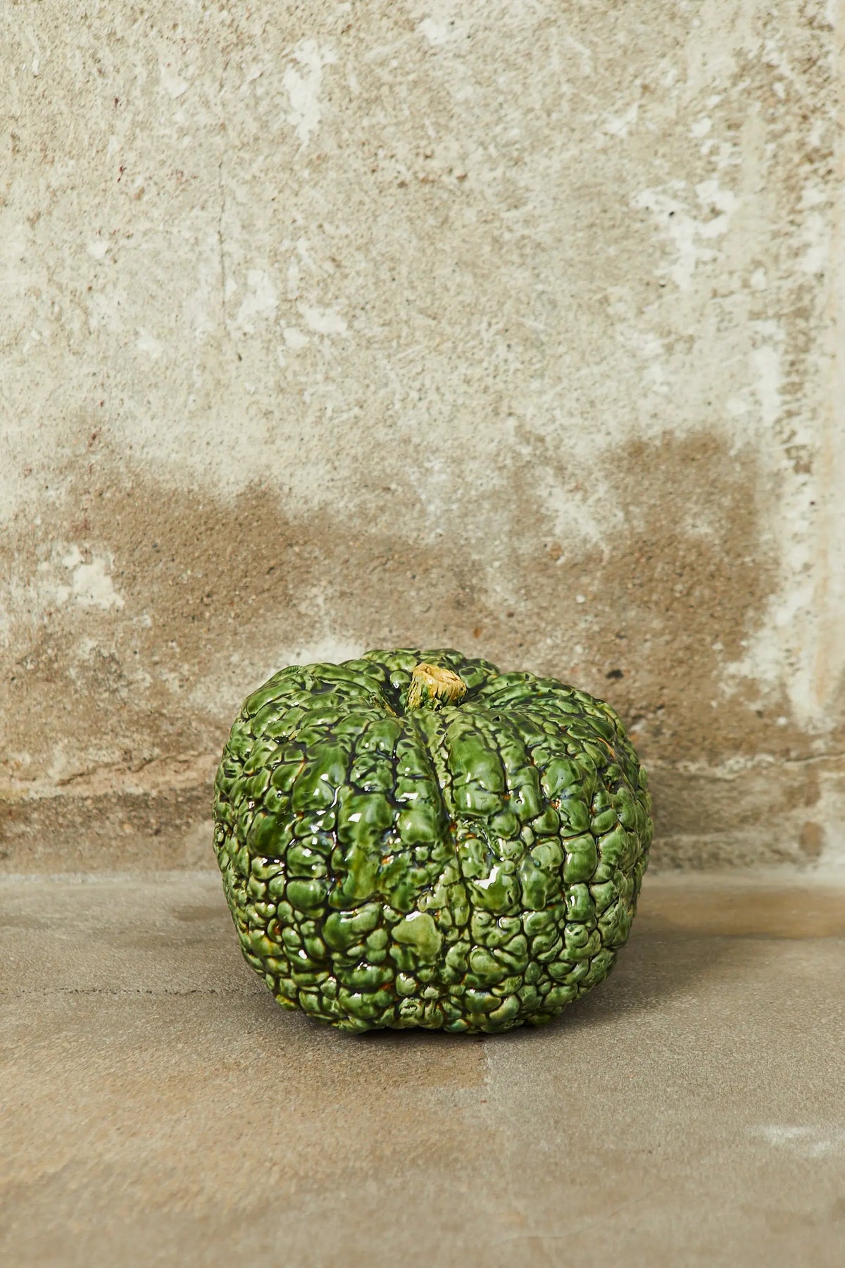 Calabaza verde brillante de cerámica con textura rugosa, ideal para decoración y estilo rústico.
