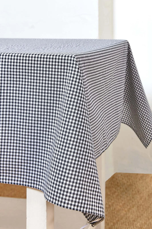 Mantel rectangular de tela con estampado de cuadros vichy en color negro y blanco sobre una mesa.