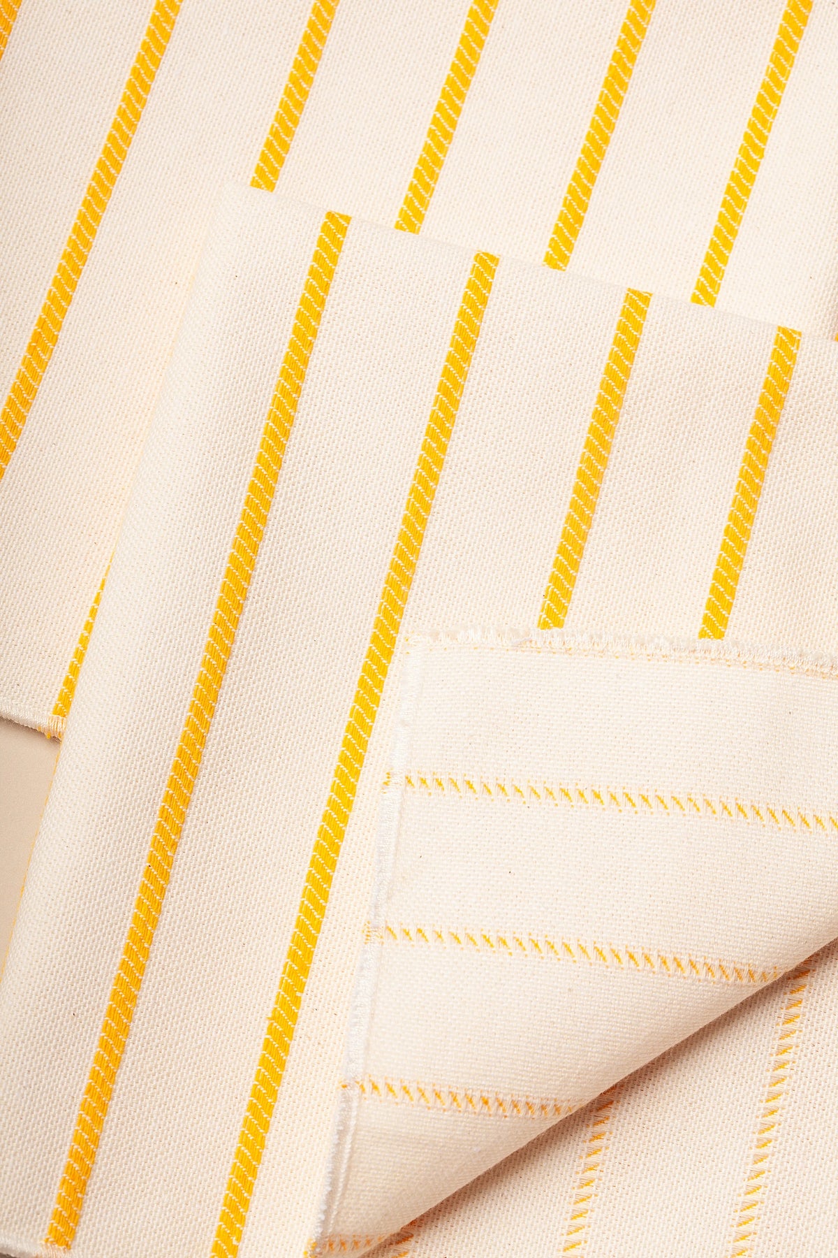Tejido de algodón beige con rayas amarillas, ideal para manualidades y decoración.