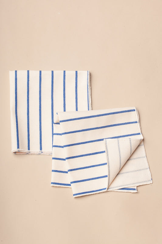Servilletas de algodón blanco con rayas azules, estilo moderno y elegante, ideales para mesas contemporáneas.