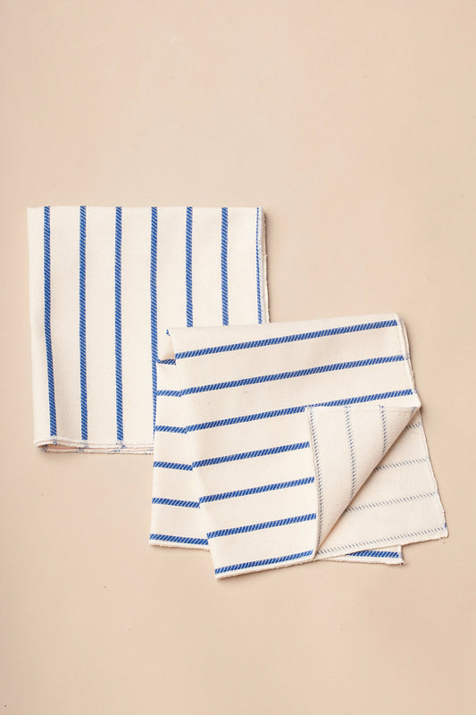 Servilletas de algodón blanco con rayas azules, estilo moderno y elegante, ideales para mesas contemporáneas.
