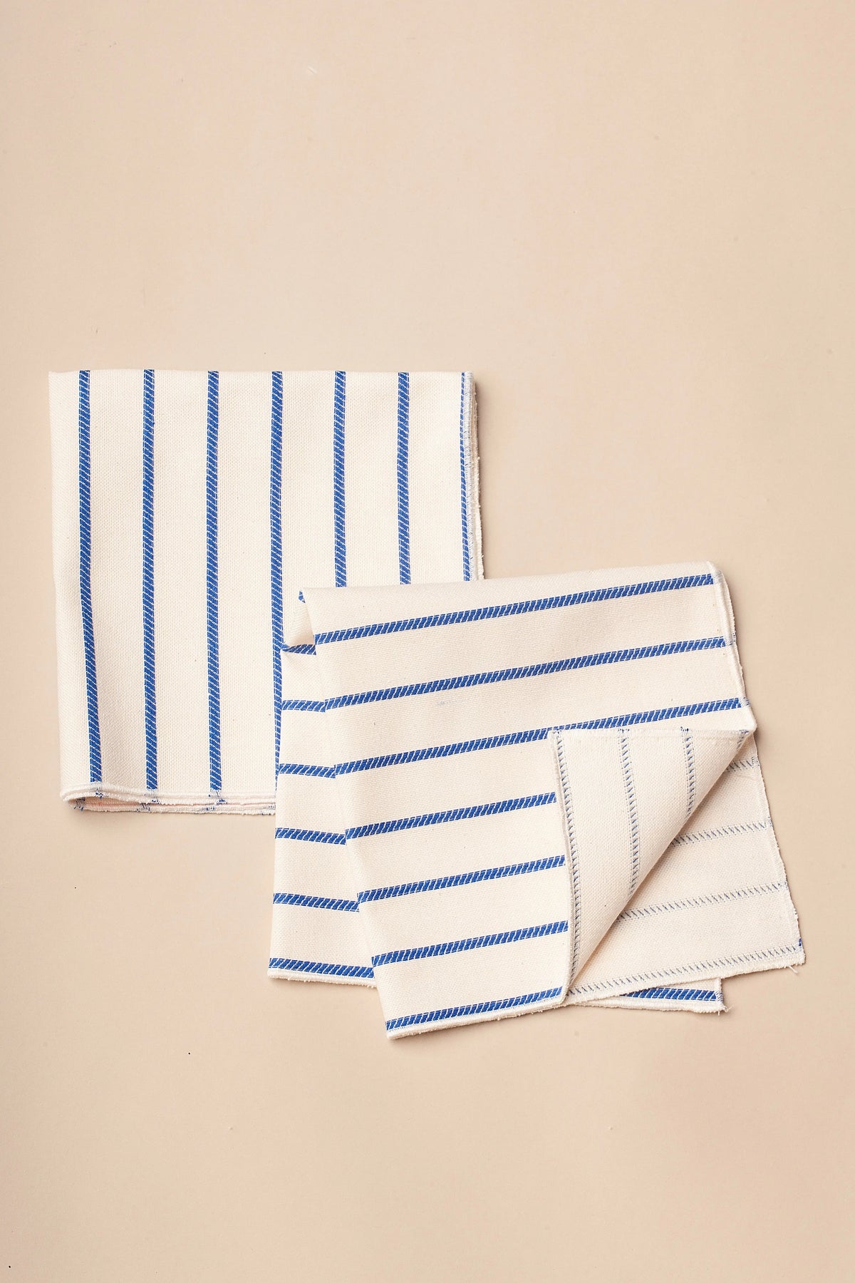 Servilletas de algodón blanco con rayas azules, estilo moderno y elegante, ideales para mesas contemporáneas.