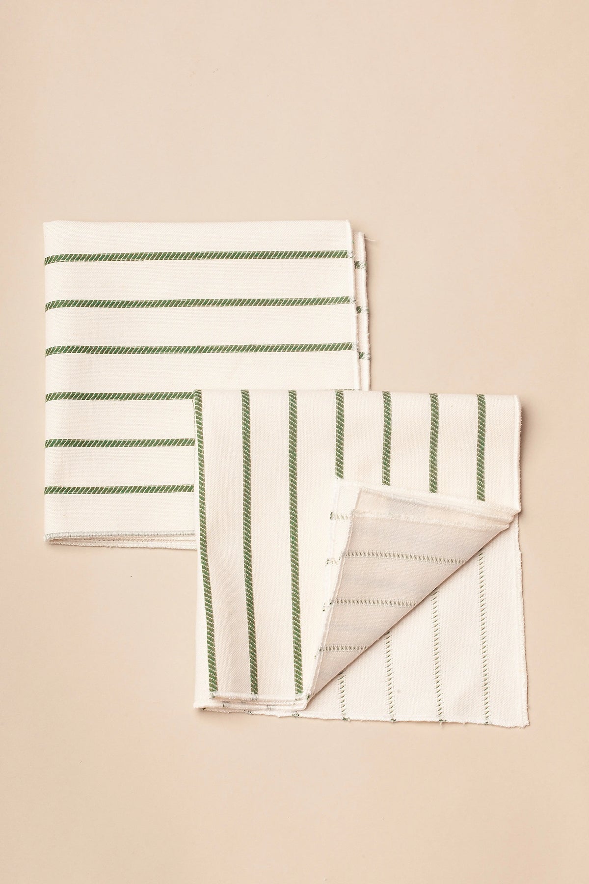 Pack de dos servilletas de tela color crema con estampado de finas rayas verticales y horizontales en color verde.