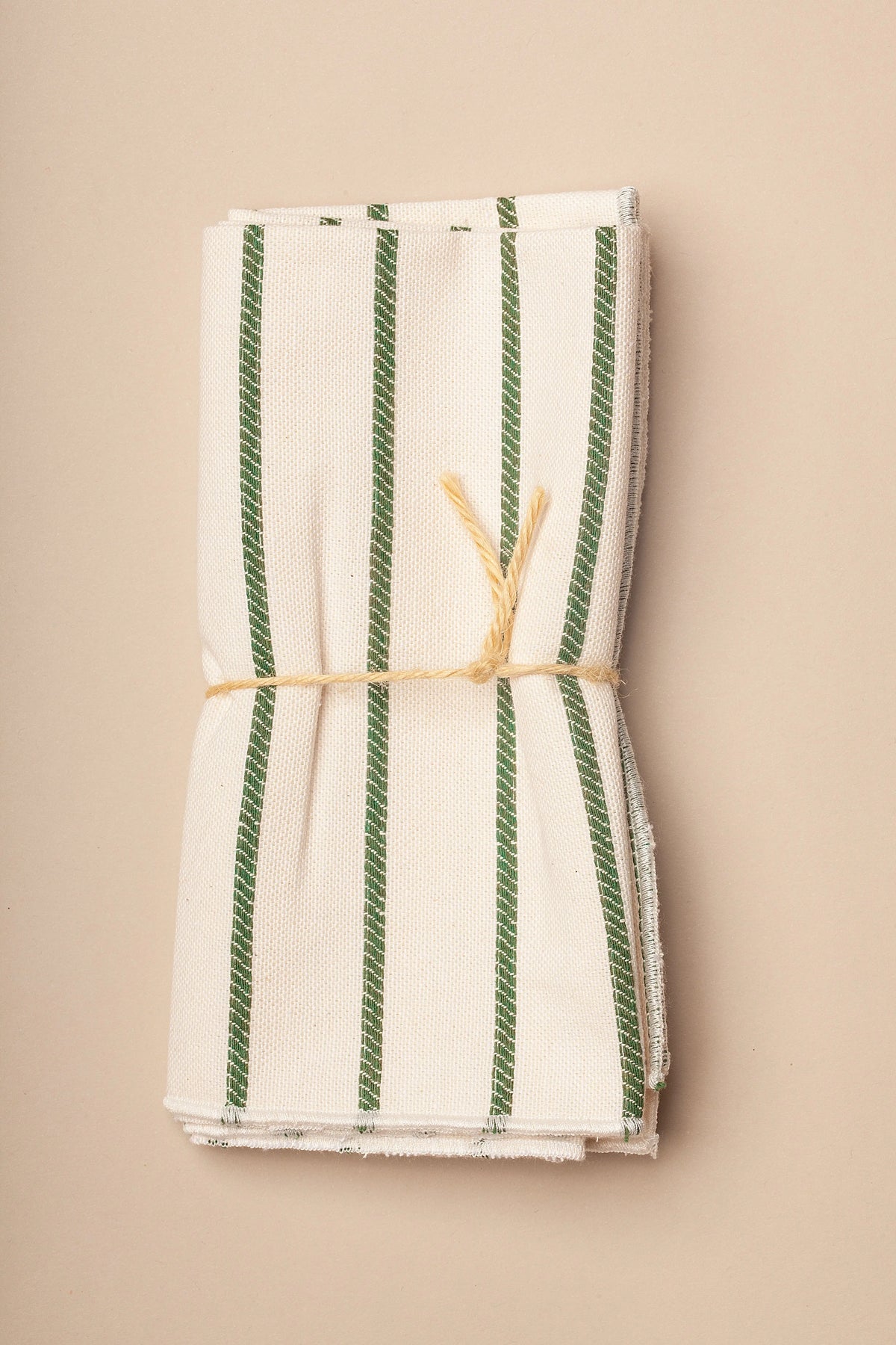 Pack de dos servilletas de tela color crema con rayas verticales verdes, atadas con una cuerda de fibras naturales.