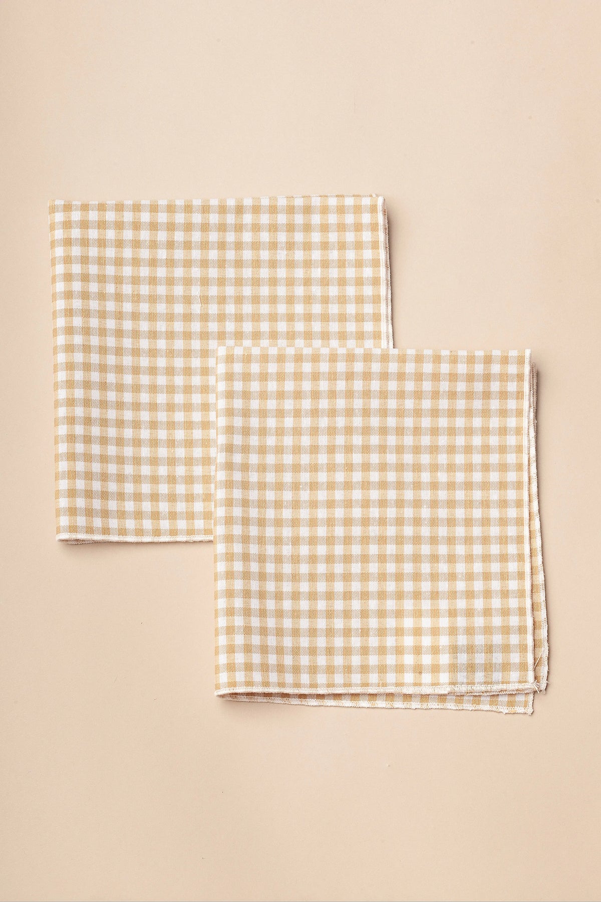 Pack de dos servilletas textiles cuadradas con estampado de cuadros vichy en color beige y blanco.