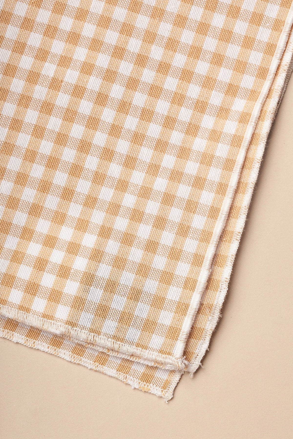 Pack de dos servilletas de tela con estampado de cuadros vichy en color beige y blanco, con bordes deshilachados.