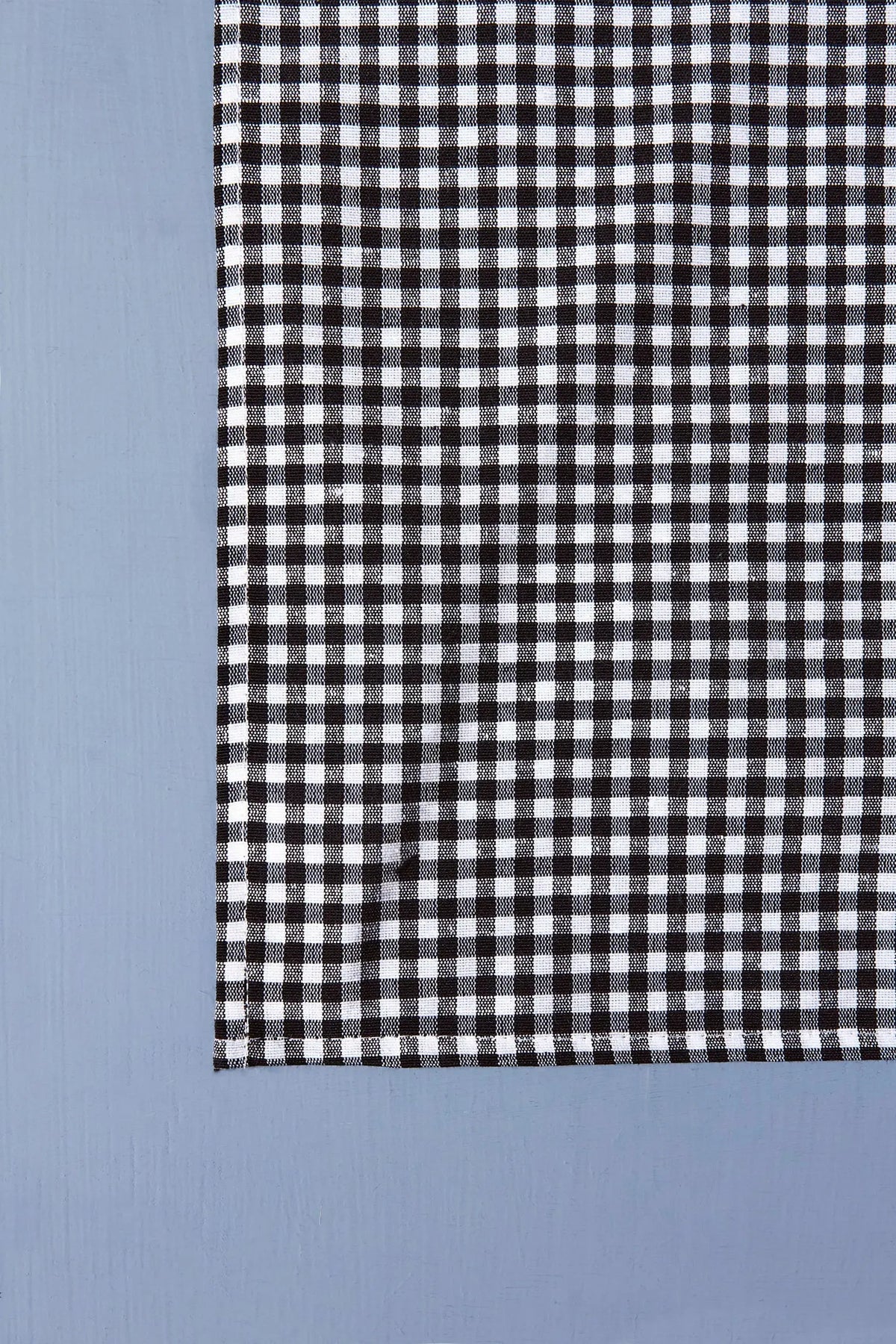Pack de dos servilletas de tela con estampado de cuadros vichy en color negro y blanco sobre fondo azul claro.