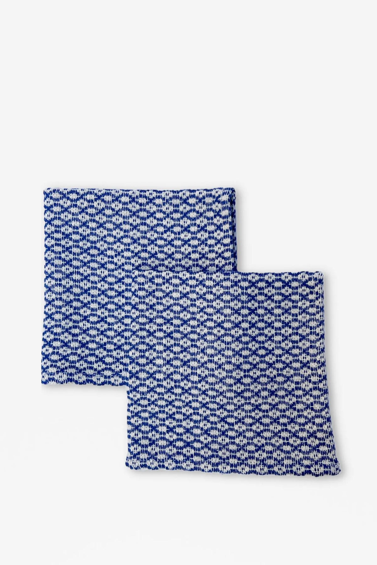Two square fabric napkins with a blue and white houndstooth or ojo de perdiz geometric pattern.