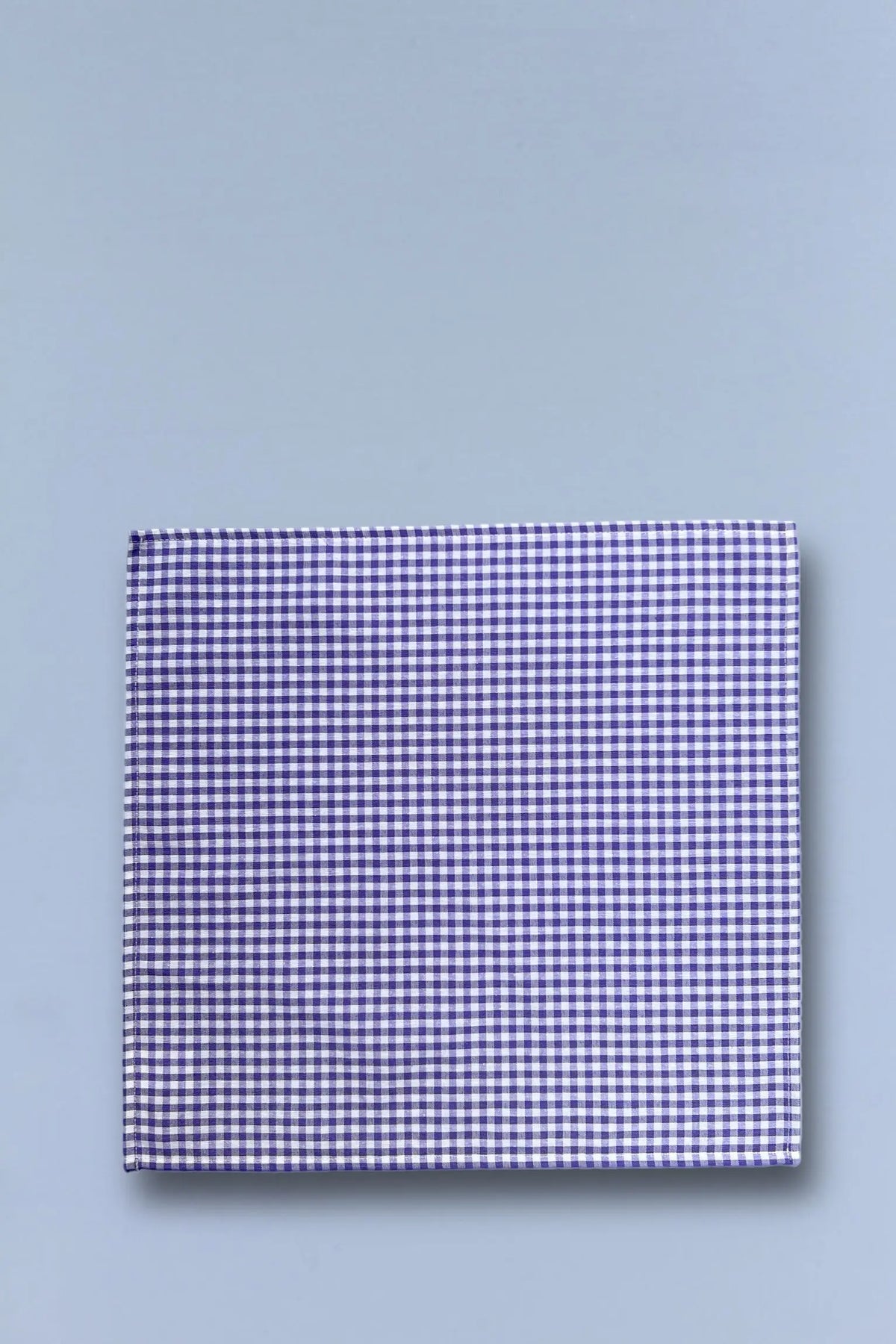 Square napkin with small purple and white gingham check pattern on a light blue background.