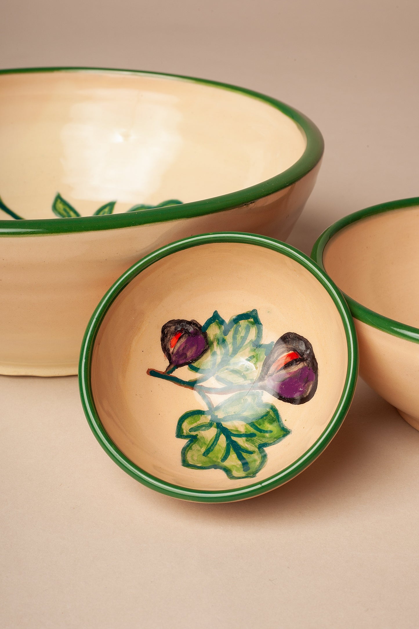 Set de cuencos de cerámica artesanal con estampado de higos y hojas, borde verde y acabado brillante.