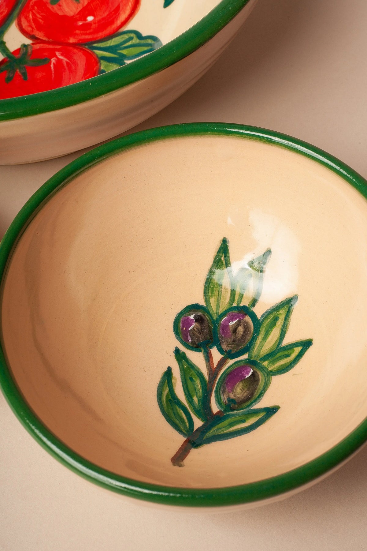 Set de cuencos de cerámica artesanal con estampado de tomates y olivas, borde verde y fondo crema.