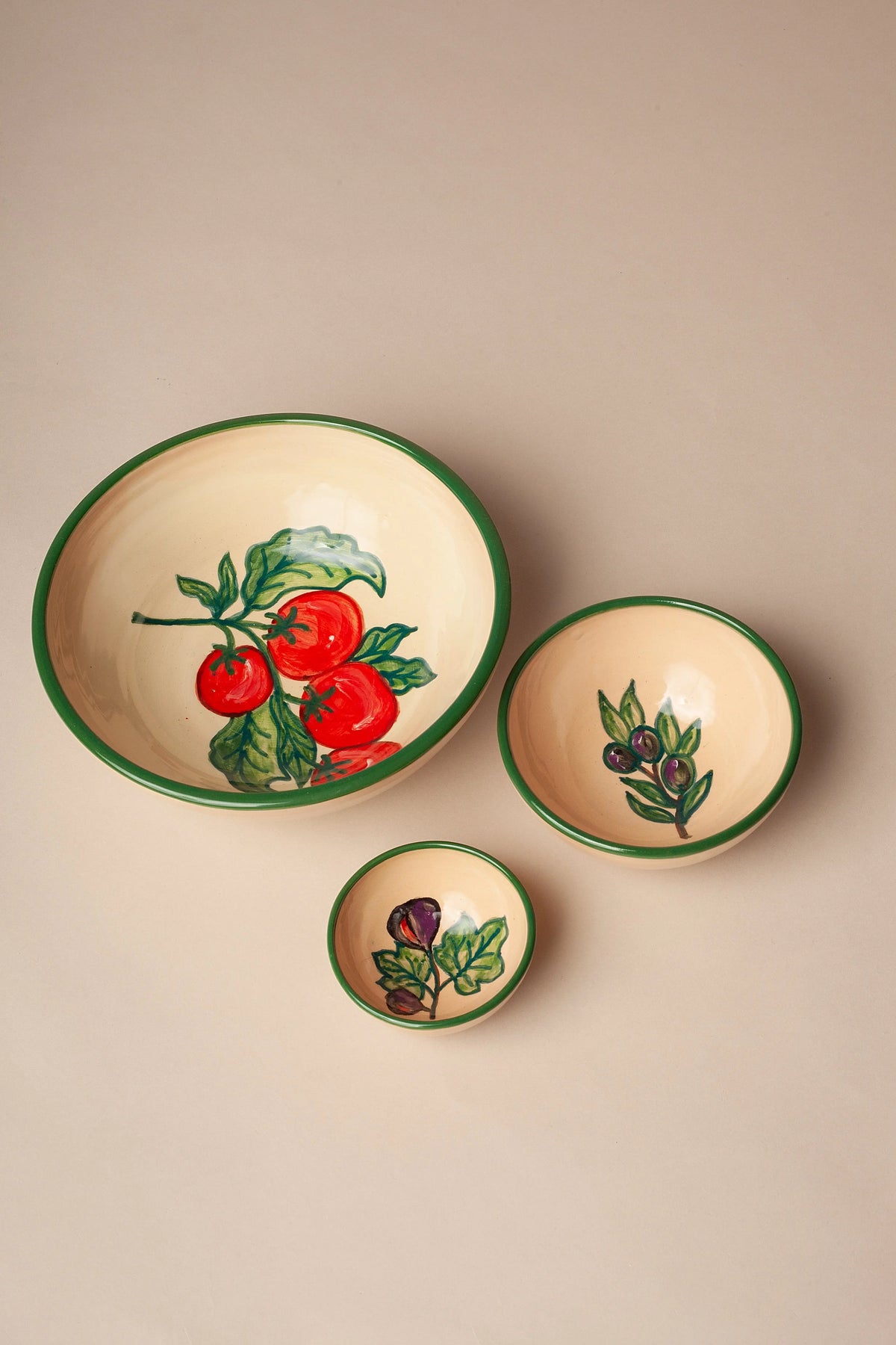 Set de tres cuencos de cerámica beige con bordes verdes y motivos pintados de tomates, aceitunas e higos.