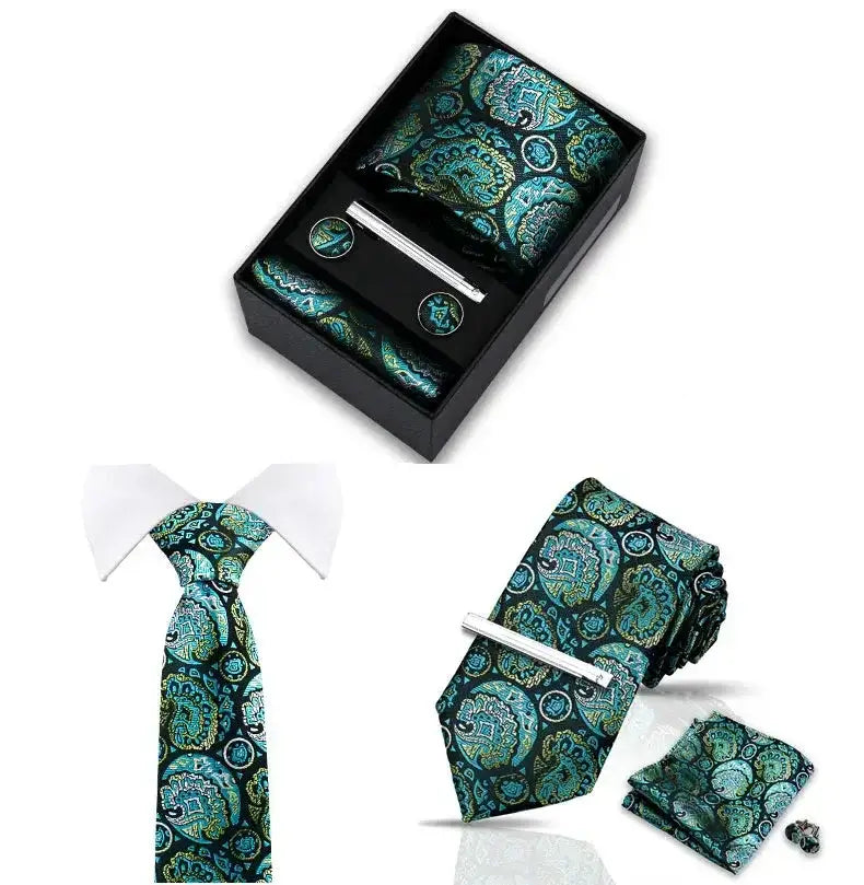 Set de corbata, pañuelo, gemelos y pasador plateado con estampado paisley en tonos verde azulado sobre fondo oscuro.