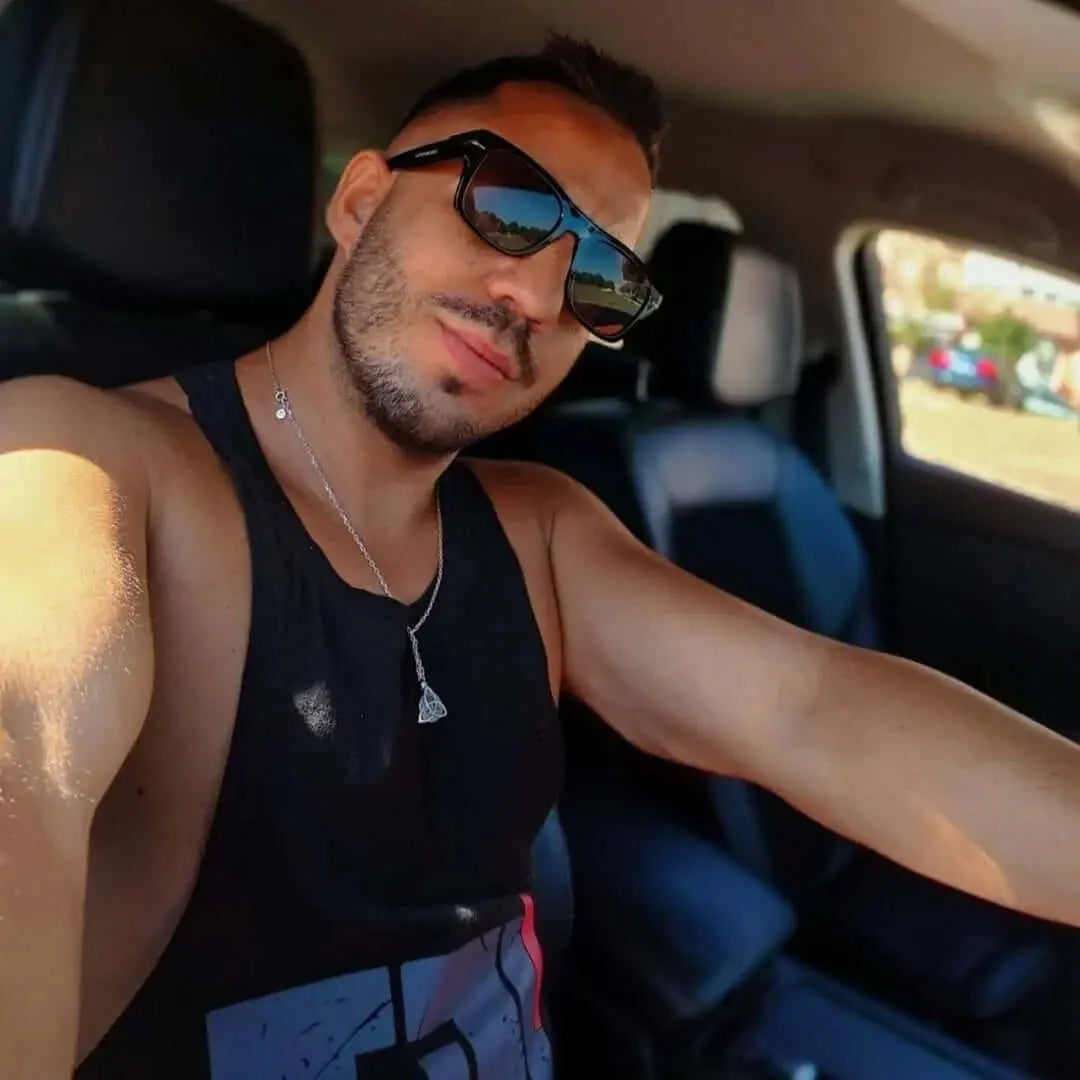 Hombre en coche usa gafas de sol retro de montura negra y cristales marrones con estilo premium.