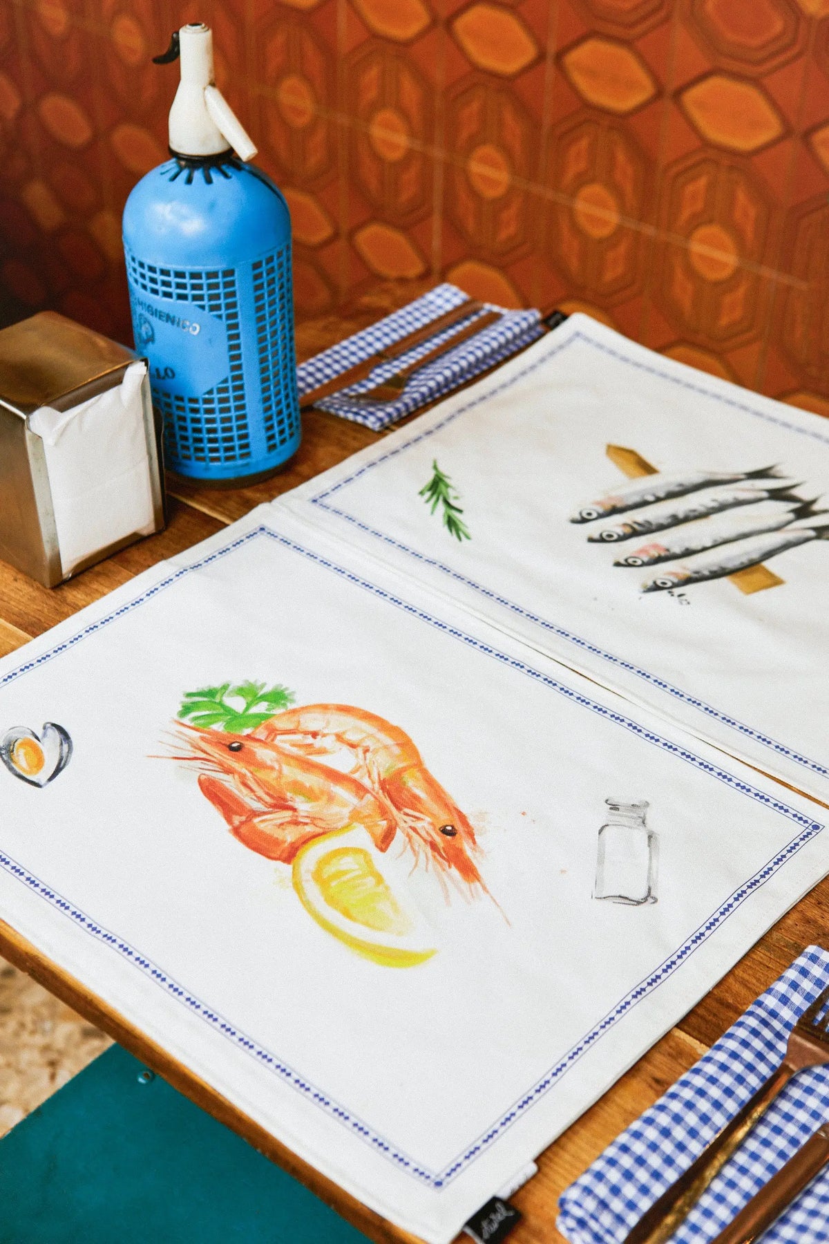 Pack de 2 manteles individuales reversibles blancos con ilustraciones de marisco, limones y pescado, estilo náutico.