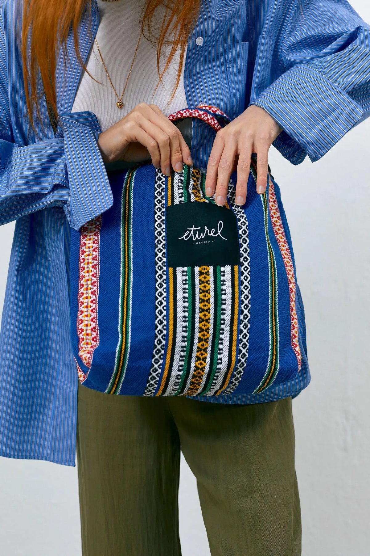 Bolso bandolera de tela azul con estampado geométrico multicolor, estilo artesanal y cierre cómodo para el día a día.
