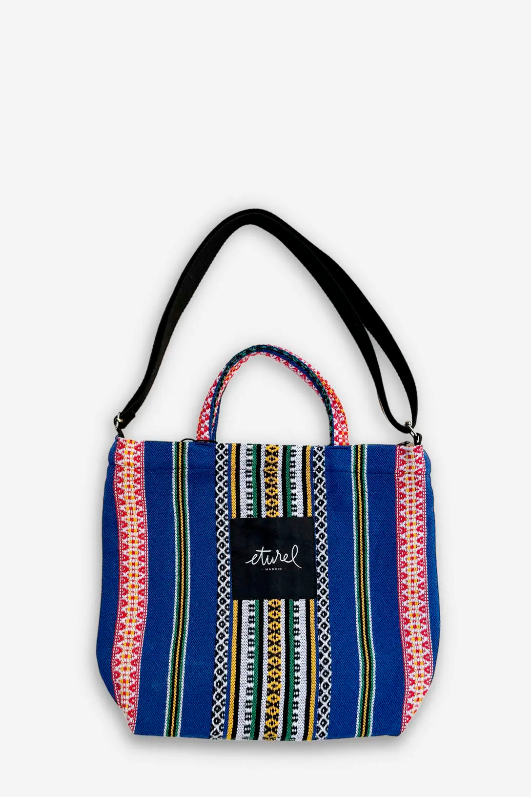 Tote bag bandolera azul de tela con estampado étnico multicolor, asas cortas y correa negra ajustable.