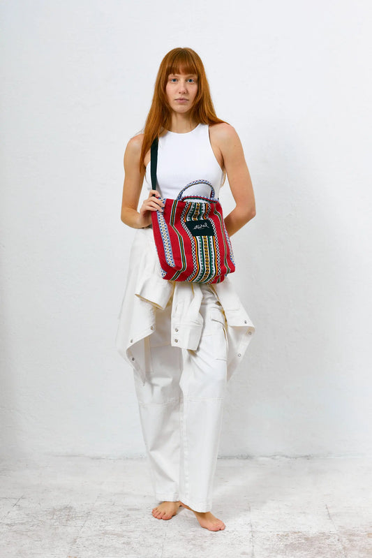 Bolso bandolera rojo de tela con estampado étnico, forma rectangular, asas cortas y correa negra cruzada.