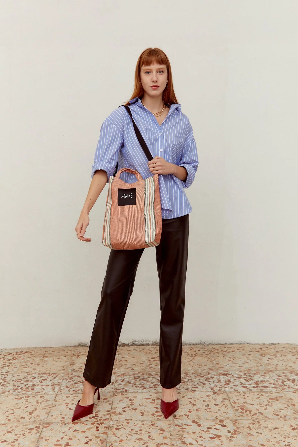 Bolso bandolera tipo tote en sarga color arcilla con detalle de rayas y correa ajustable sobre fondo neutro.
