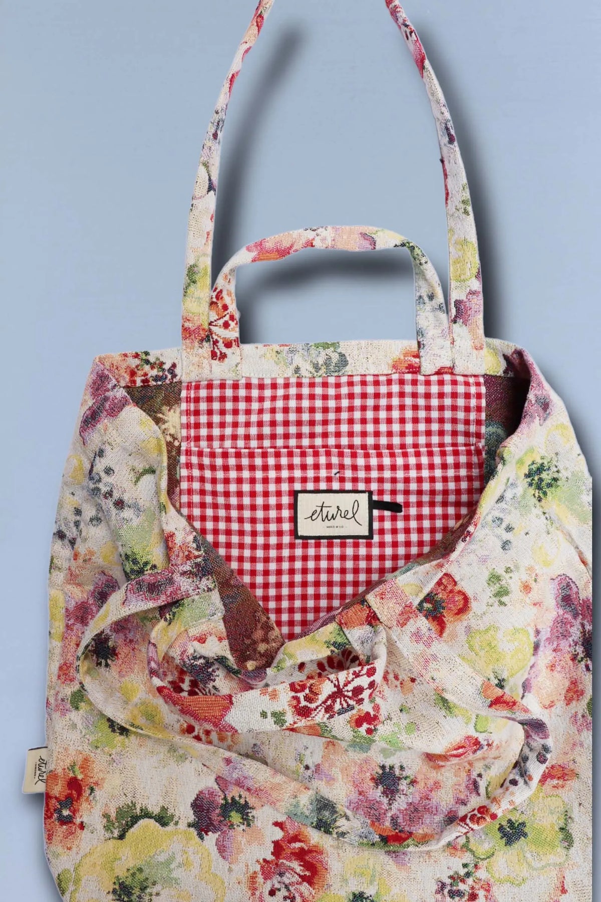 Tote bag de tejido jacquard con estampado de amapolas coloridas y forro interior de cuadros vichy rojos.