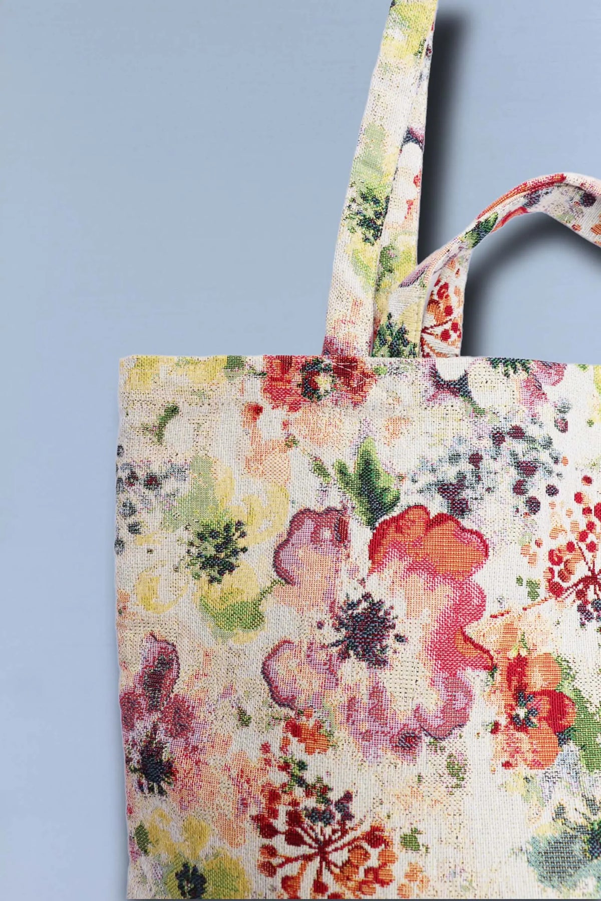 Tote bag de tela jacquard con estampado floral de amapolas en tonos coloridos sobre fondo claro, estilo artesanal.